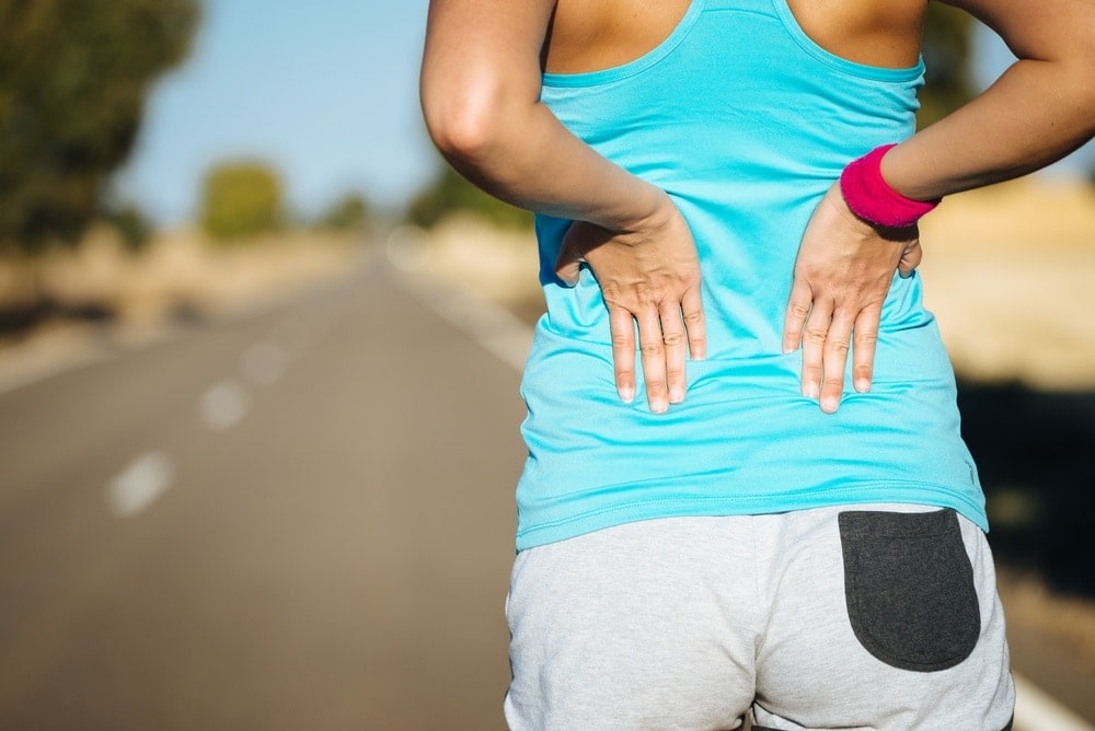 muscle-cramps-during-pregnancy-woman-running-hands-holding-lower-back | American Pregnancy Association