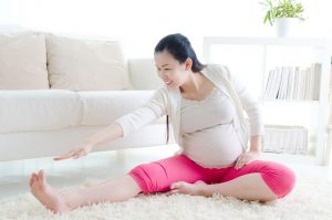 Pregnant woman stretching trying to prevent muscle cramps